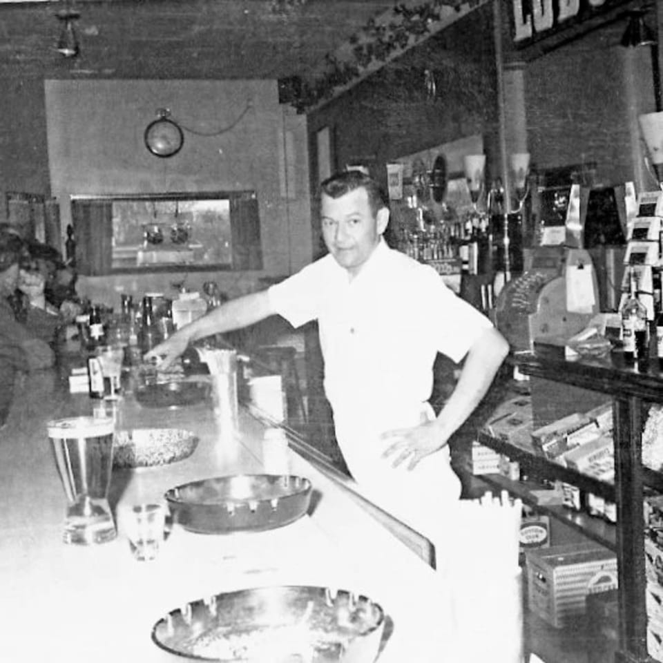A man in a white shirt stands behind a counter with bowls and drinks at Uncle Lenny's Country Cafe.