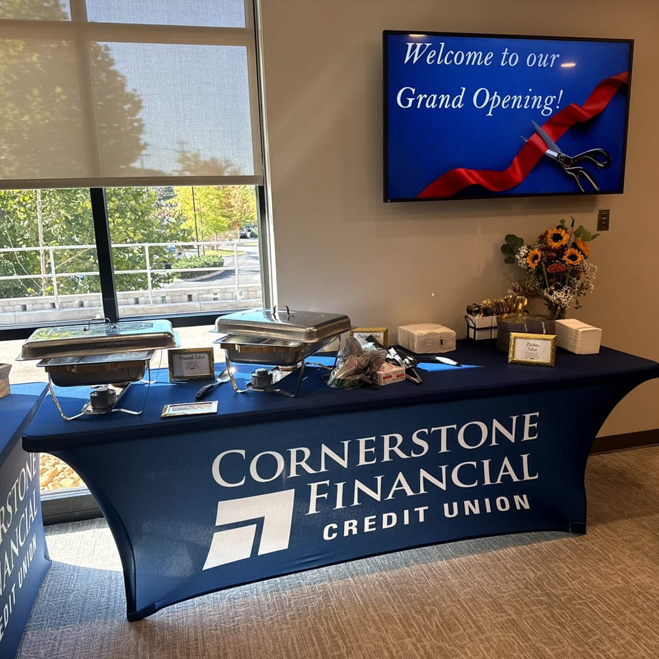 A buffet table with chafing dishes and a "Welcome to our Grand Opening!" screen.